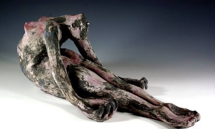 A reclining figure mottled pink and black, arching back with one arm folded over her head and her long legs stretched out