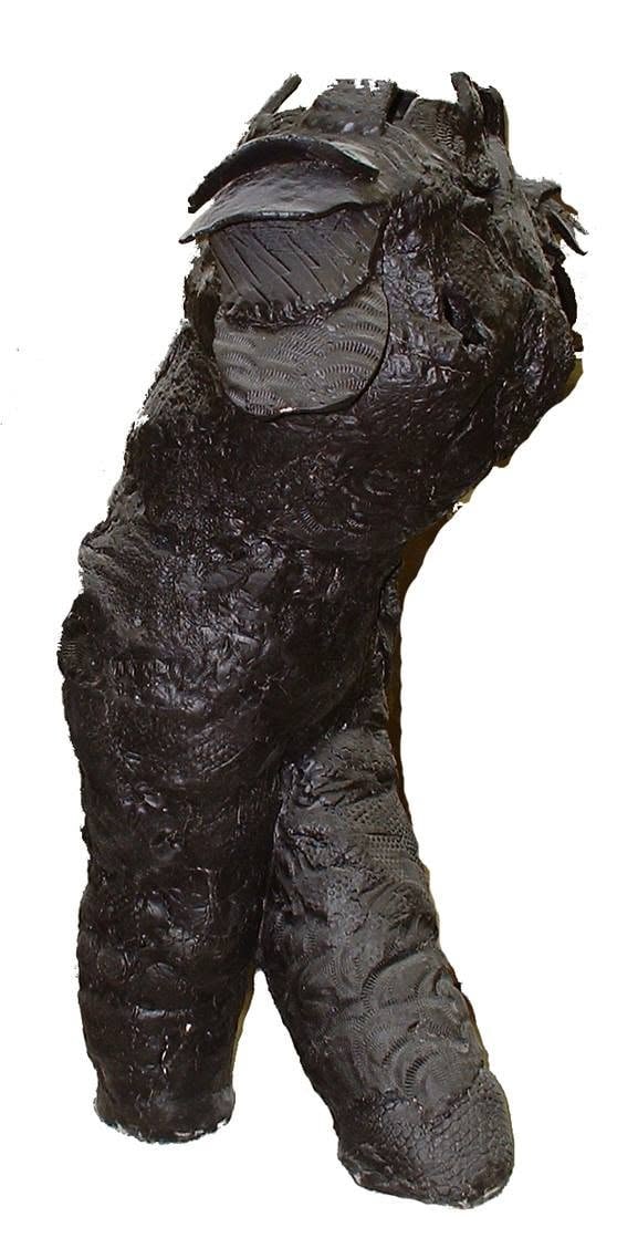 A tall black figure from shoulders to feet, twisting at the waist, its whole surface pressed with lace and reptile-like textures
