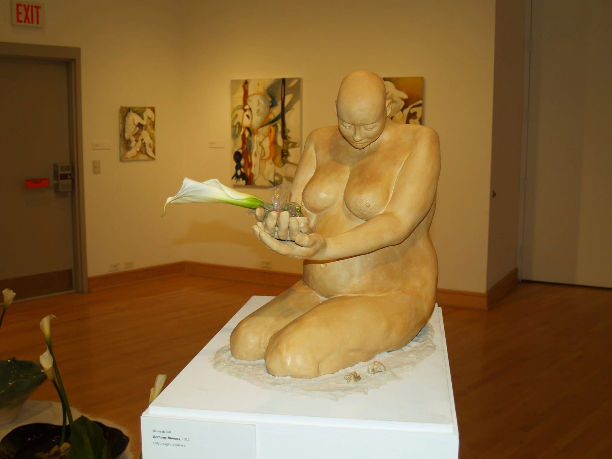 Her kneeling terracotta figure offering a single white calla lily